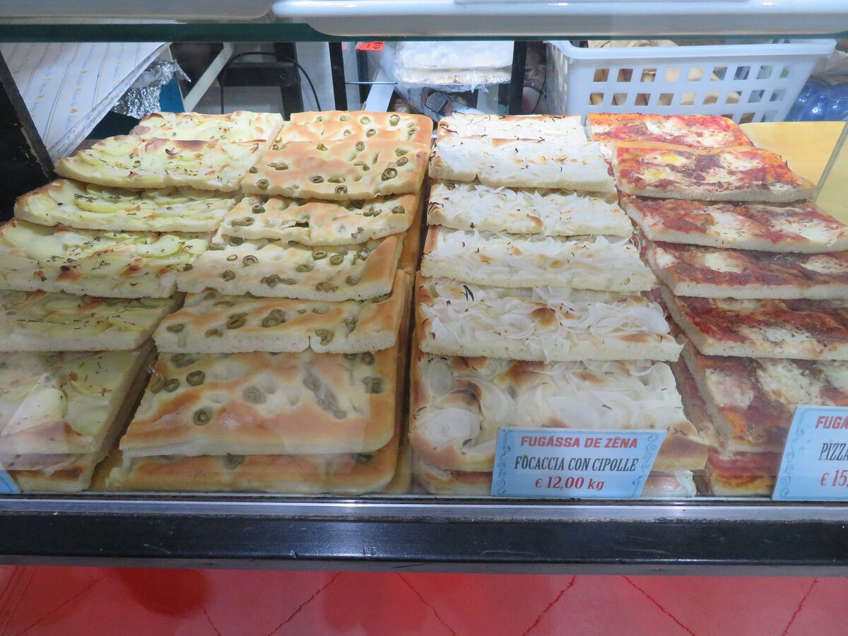 Slabs of focaccia with olives, onion and potato in a bakery display