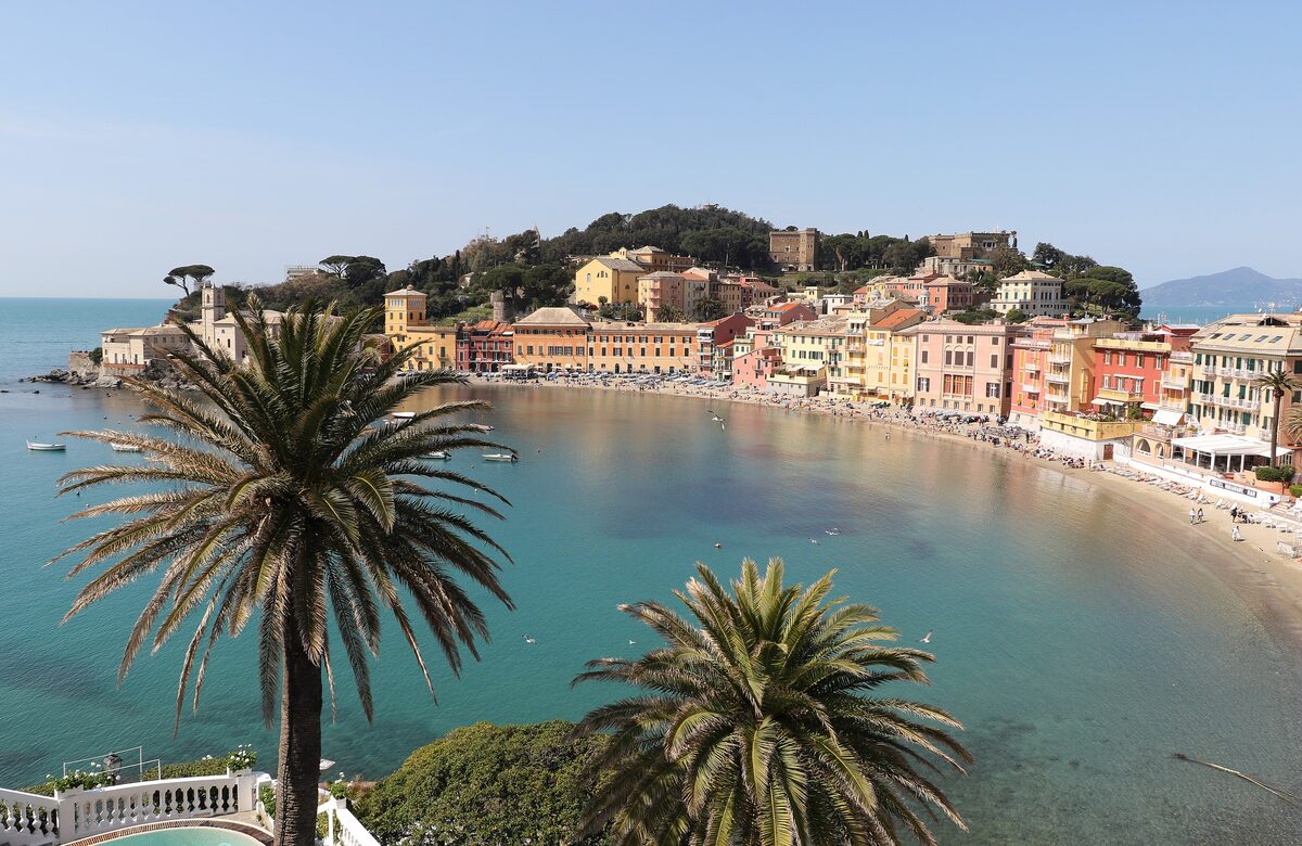 The curved beach of the Bay of Silence at Sestri Levante with palms and pastel houses