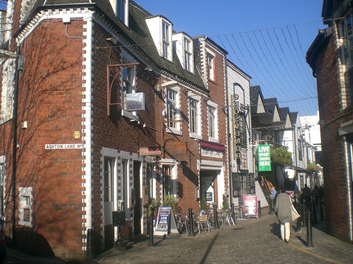 The narrow cobbled Ashton Lane in Glasgow's West End, lined with pubs and restaurants under strings of lights