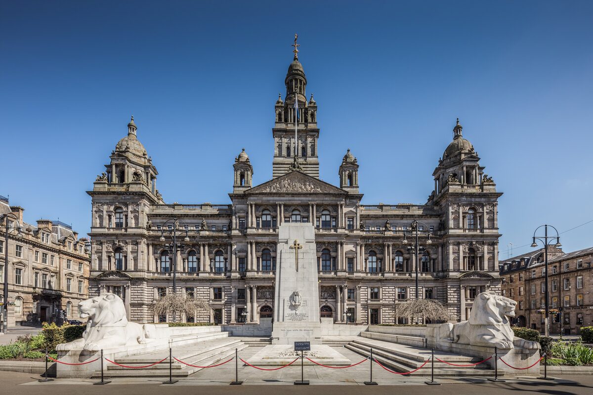 The ornate Victorian front of Glasgow City Chambers on George Square, with the cenotaph and stone lions in front