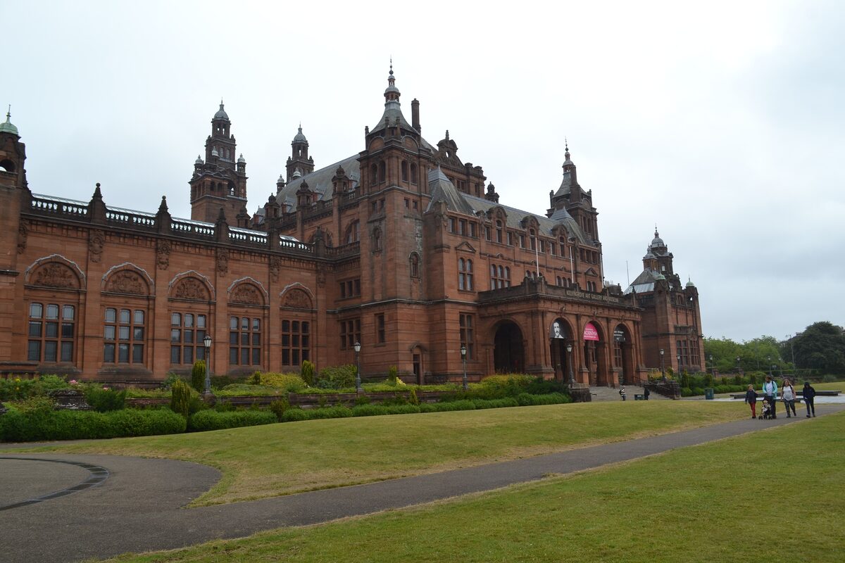 The red sandstone towers and front of Kelvingrove Art Gallery and Museum behind a lawn