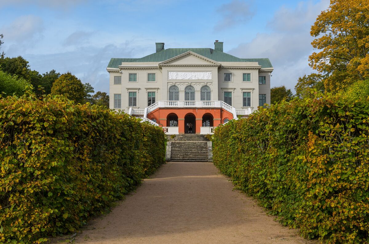 The white neoclassical Gunnebo House at the end of a path between tall clipped hedges