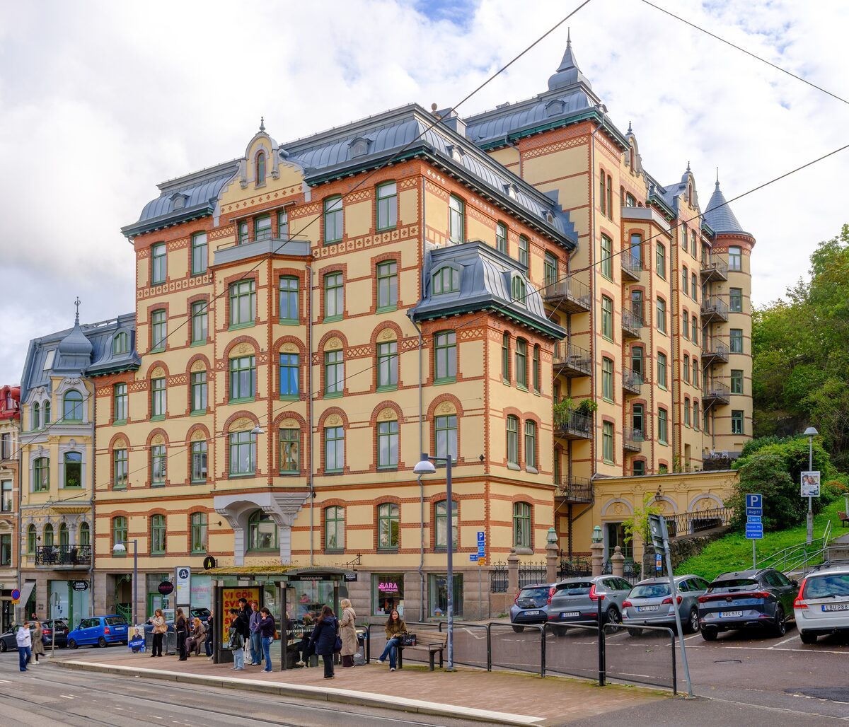 A tall, ornate yellow and red brick apartment building with turrets on a corner in Haga, Gothenburg