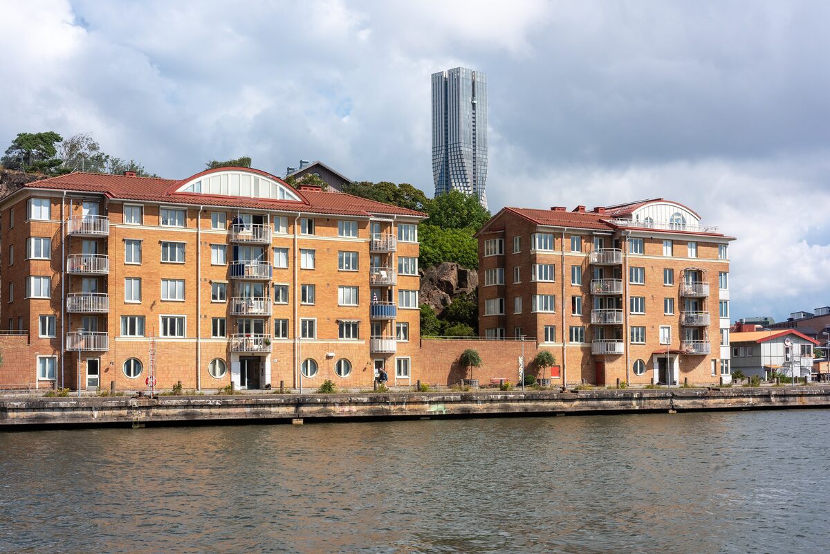 The slim grey Karlatornet skyscraper rising behind brick apartment buildings on the waterfront of Hisingen