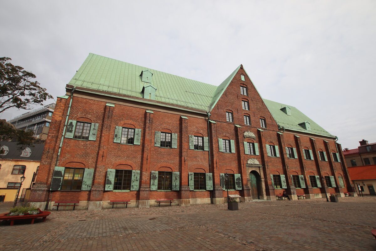 The red-brick Kronhuset with its green copper roof and stepped gable on a cobbled square