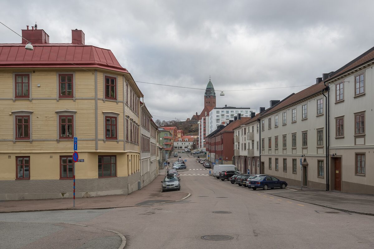 A quiet street in Majorna lined with old yellow and white houses, with a church tower at the end