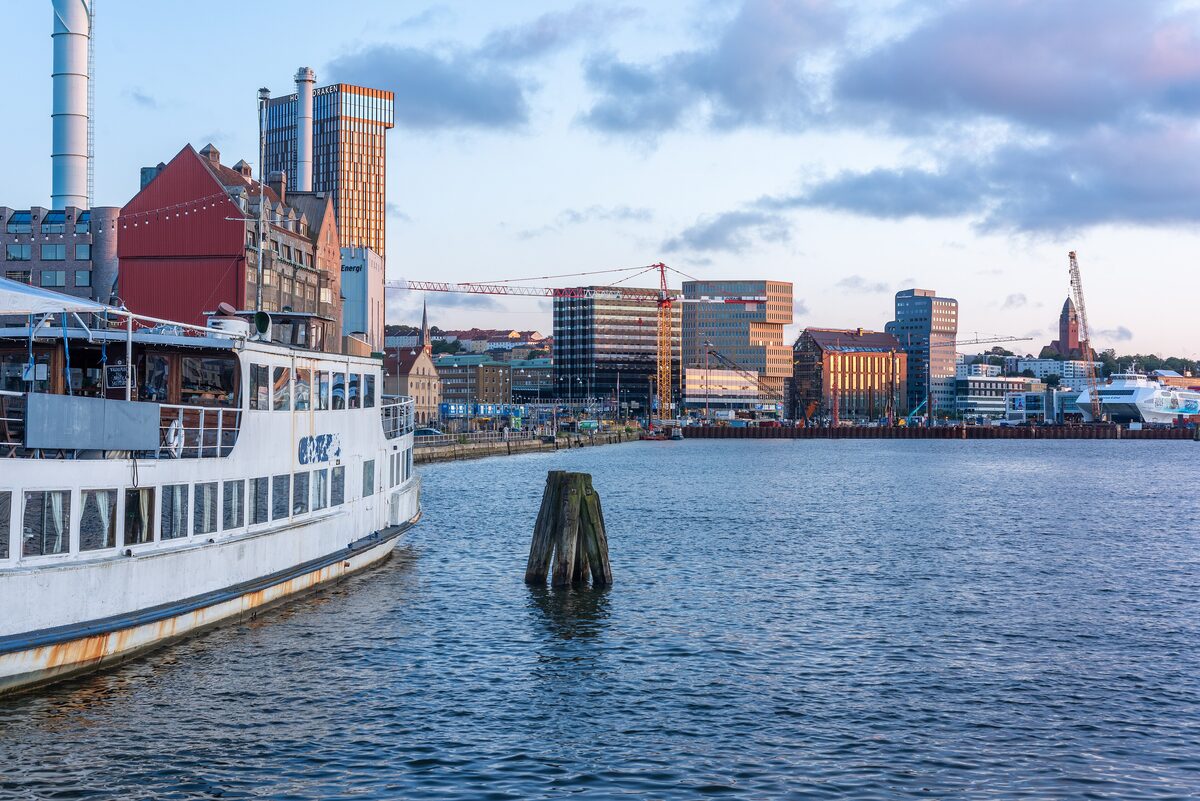 An old white passenger ship moored at the Masthugget quay with Gothenburg's new waterfront buildings behind