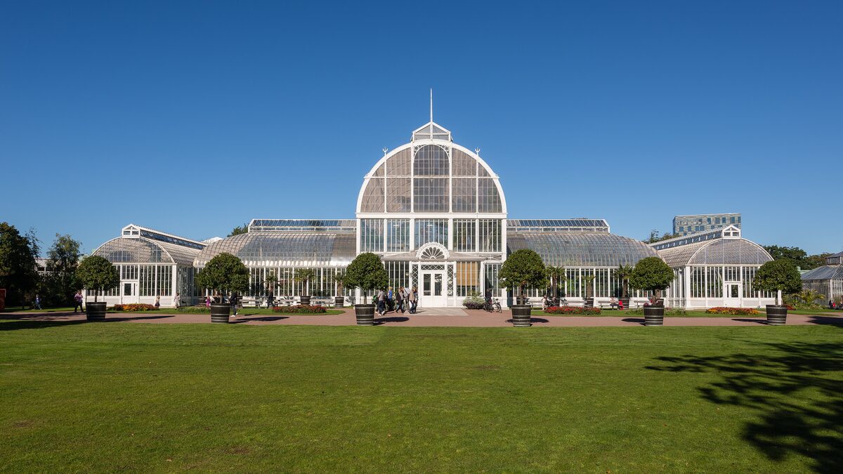The white glass Palm House in Trädgårdsföreningen with its domed central hall behind a green lawn