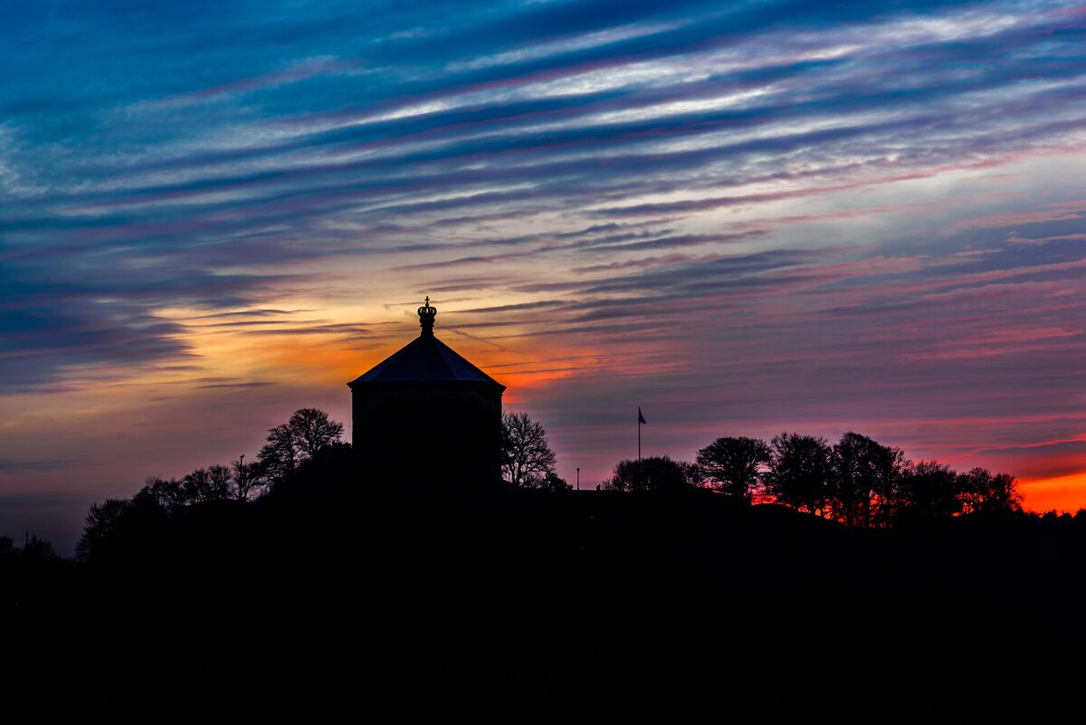 The silhouette of the Skansen Kronan fortress tower on its hill against a red and blue sunset sky