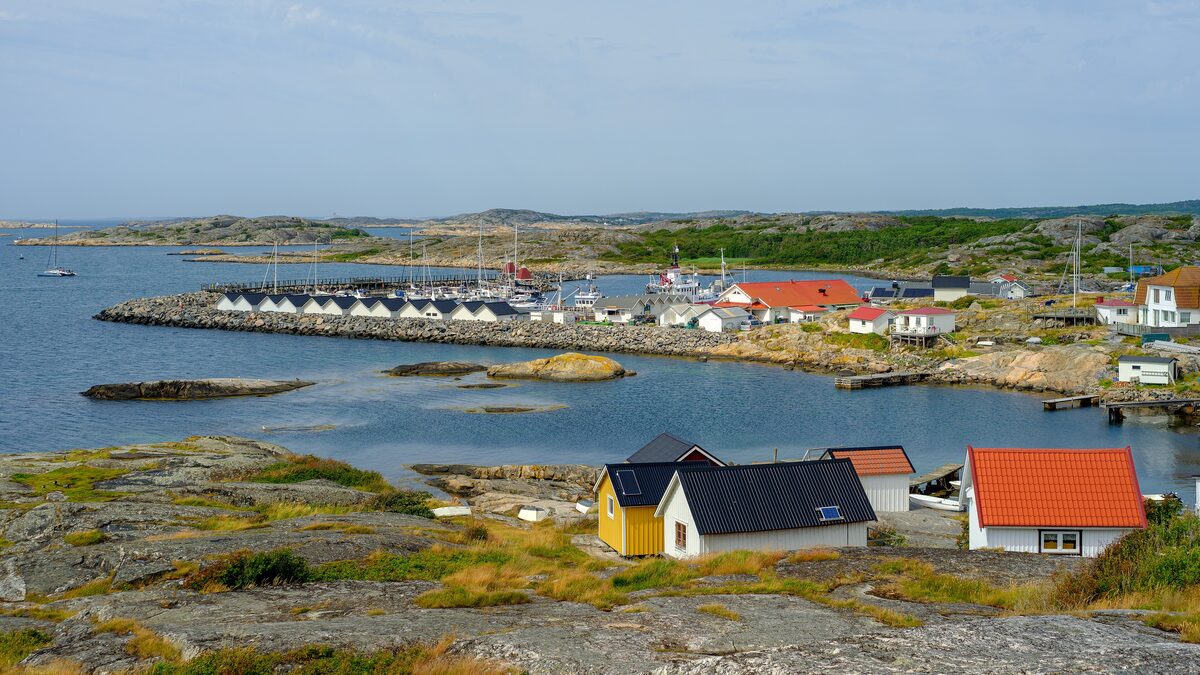 Small red and white houses on bare granite rocks by the sea on Vrångö, with a harbor and boats behind