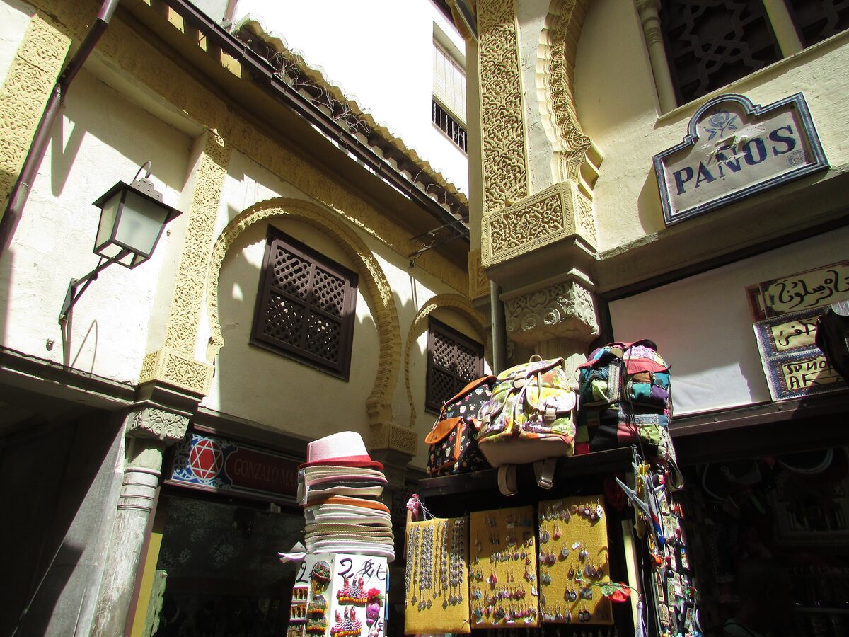 A narrow lane of the Alcaicería with horseshoe arches, carved plaster and souvenir stalls