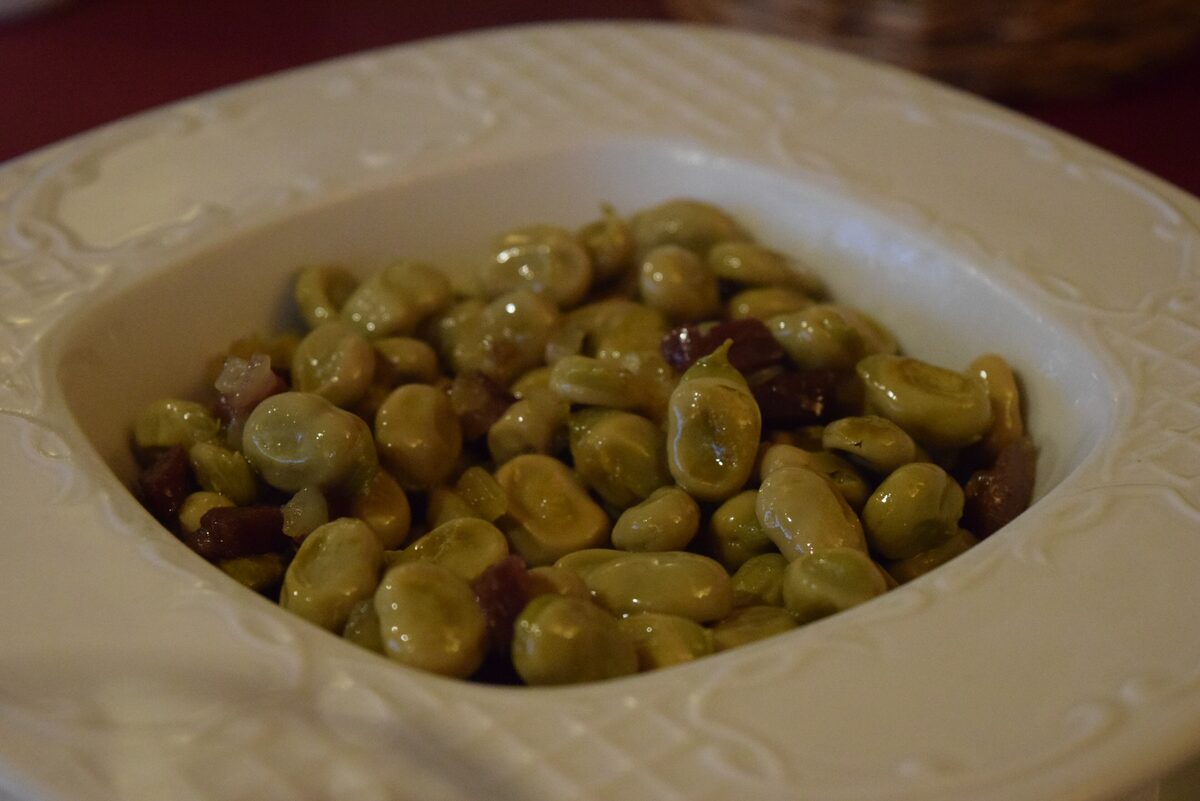 A plate of baby broad beans sautéed with pieces of cured ham