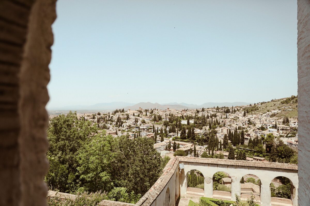 The white houses and gardens of the Albaicín spread over the hillside, seen through a window in the Alhambra walls
