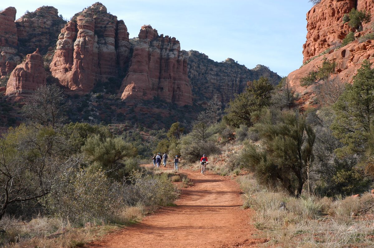 Hikers on the Bell Rock Pathway below red sandstone buttes