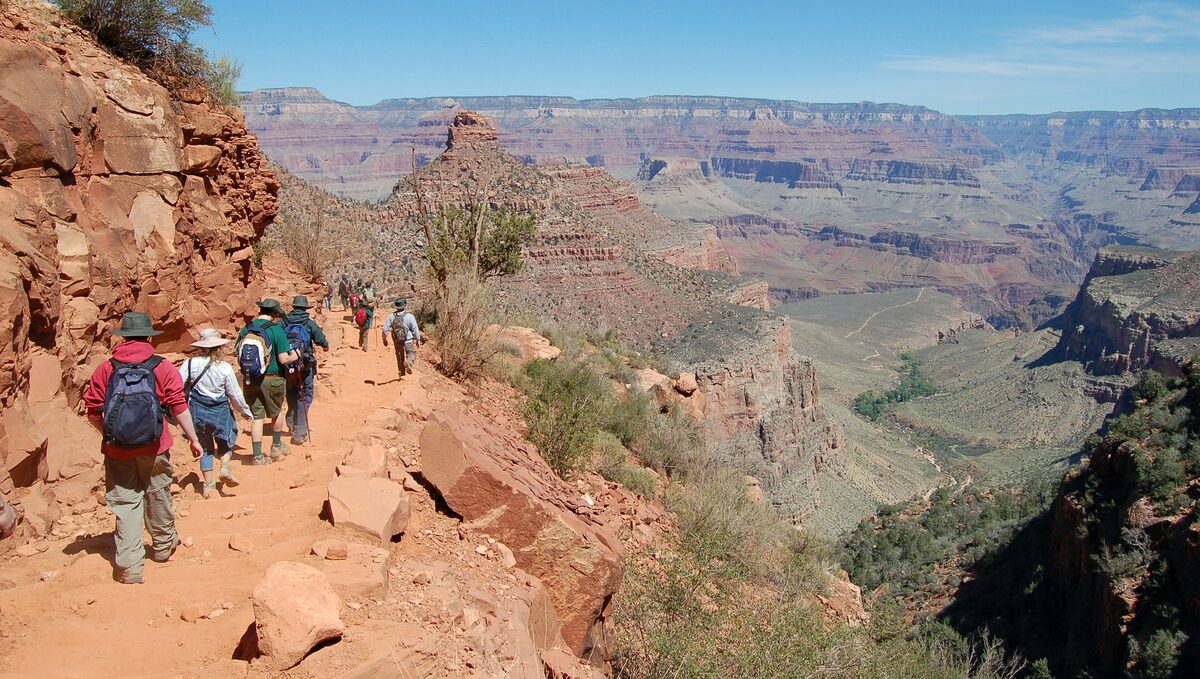 Hikers in a line descending the red Bright Angel Trail into the canyon