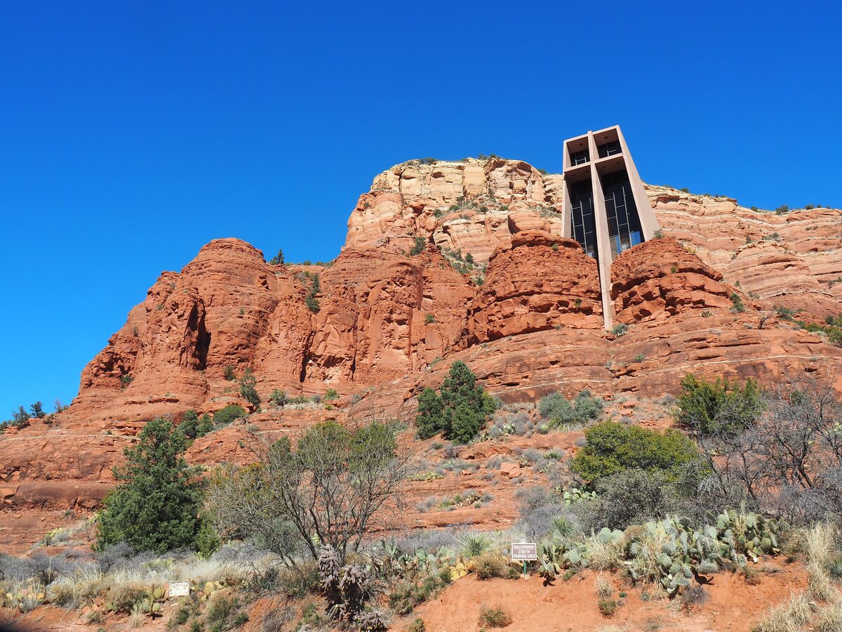 The Chapel of the Holy Cross rising from red rock cliffs under blue sky