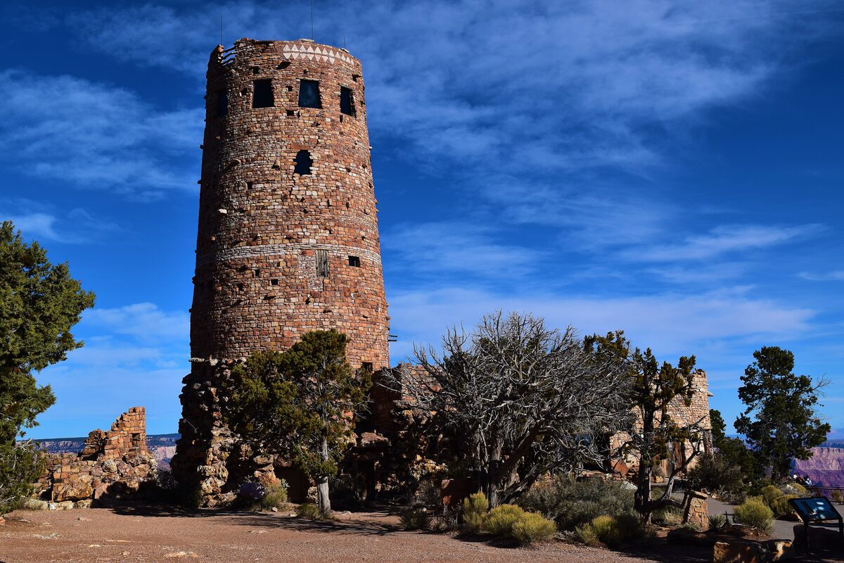 The Desert View Watchtower, a round stone tower, under blue sky and clouds