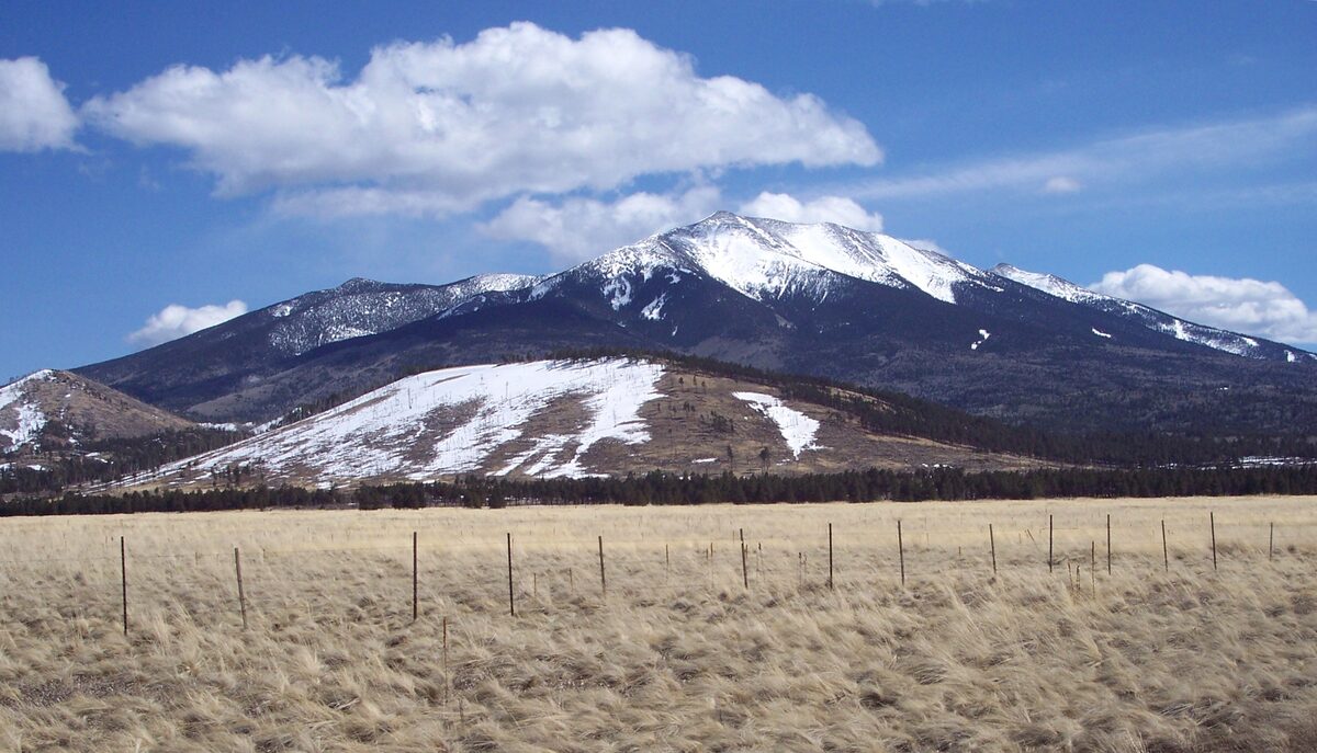 Snow-capped Humphreys Peak rising above dry grassland on a sunny day