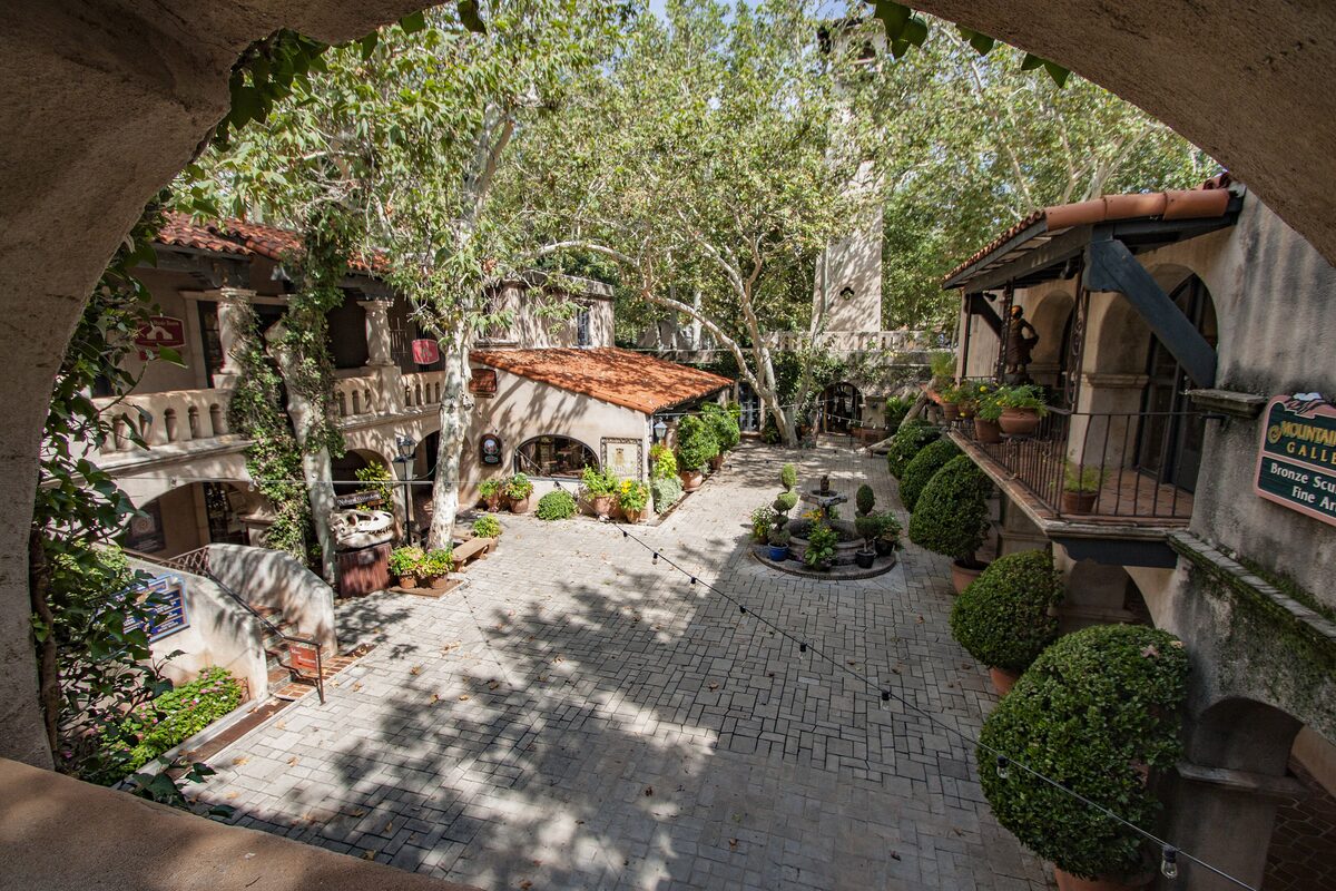 Tlaquepaque courtyard with trees and Spanish-style arcades seen through an arch
