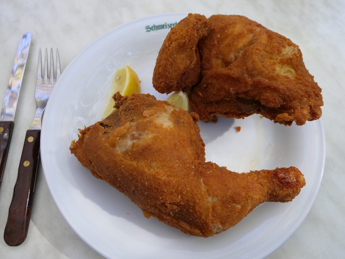 Pieces of breaded and fried chicken with a lemon wedge on a white plate