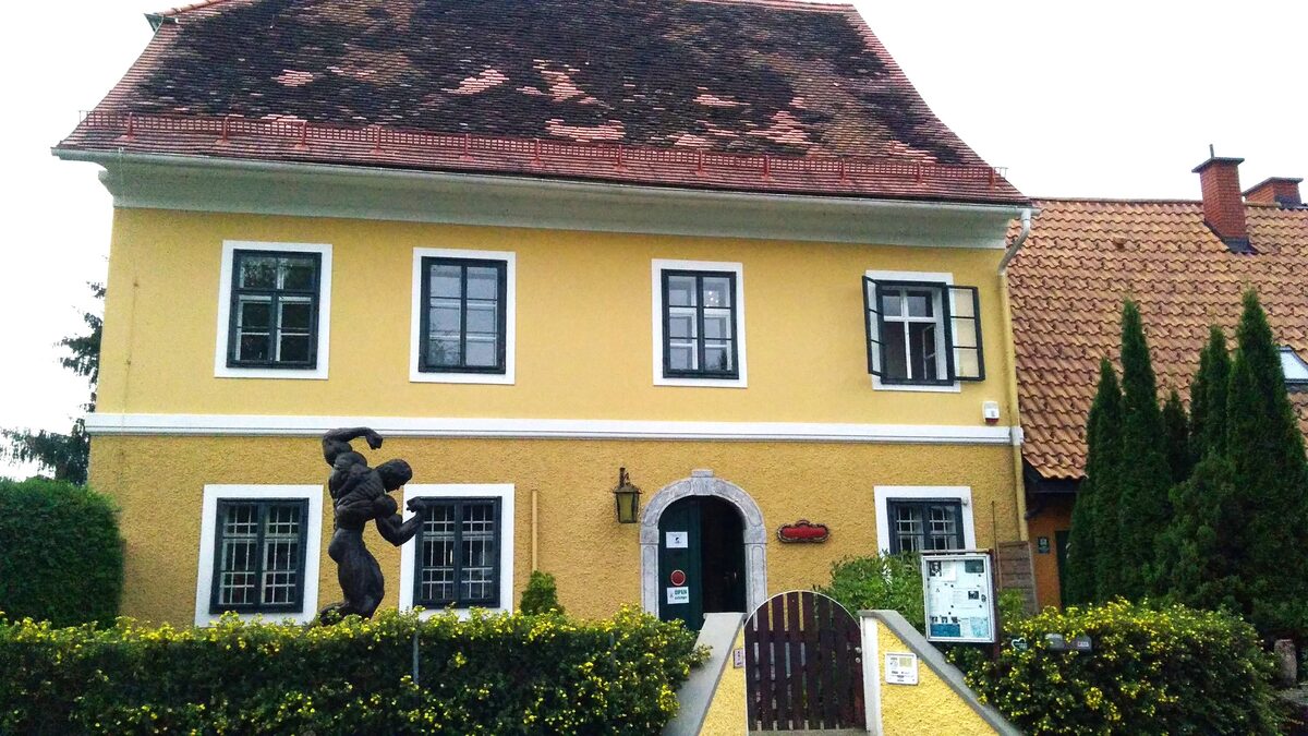 The yellow house in Thal where Arnold Schwarzenegger grew up, with a statue of him in the garden