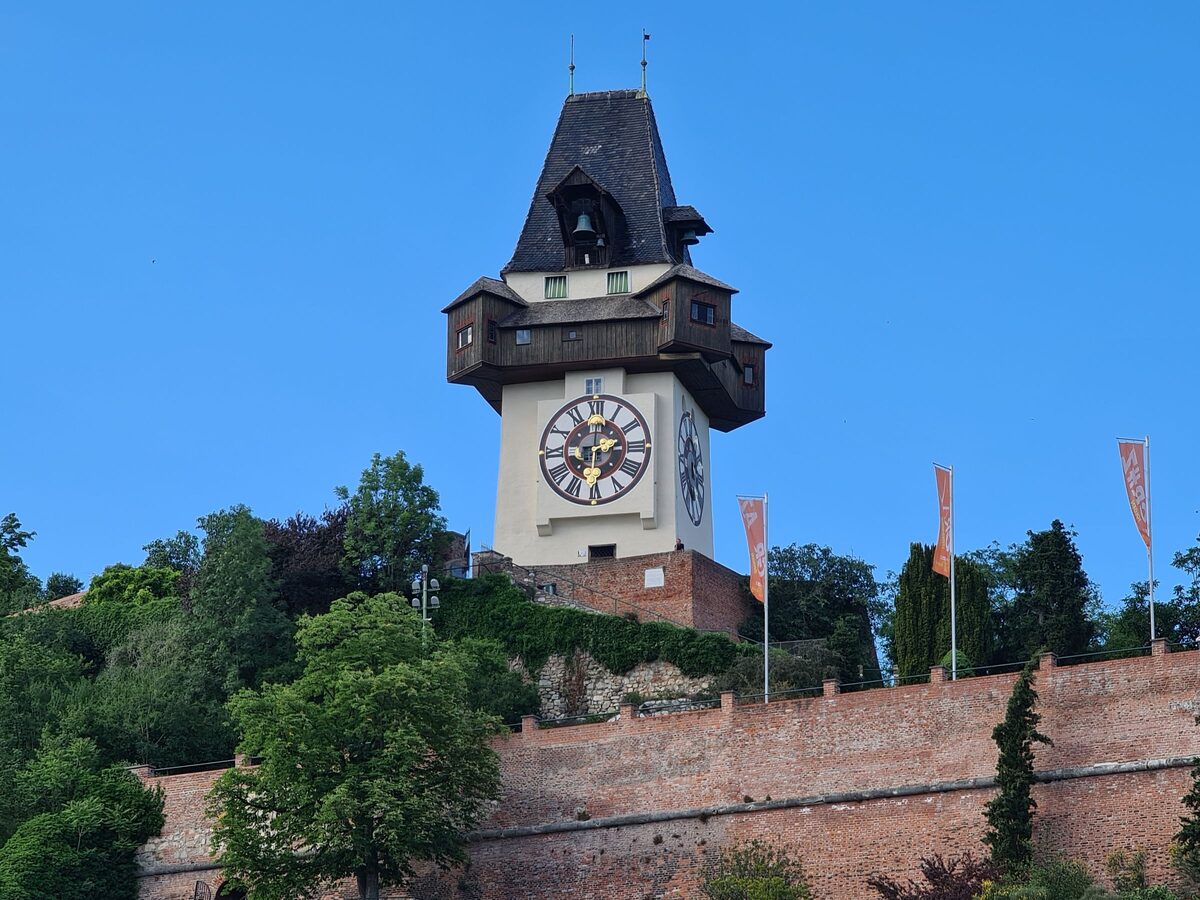 The Uhrturm, the white clock tower with a dark wooden gallery and a large clock face, on the bastion of the Schlossberg