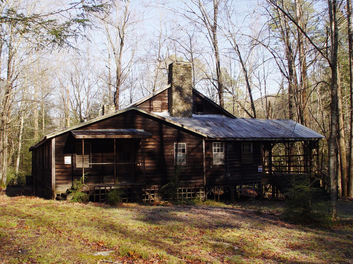 A weathered log cabin with a stone chimney at Elkmont