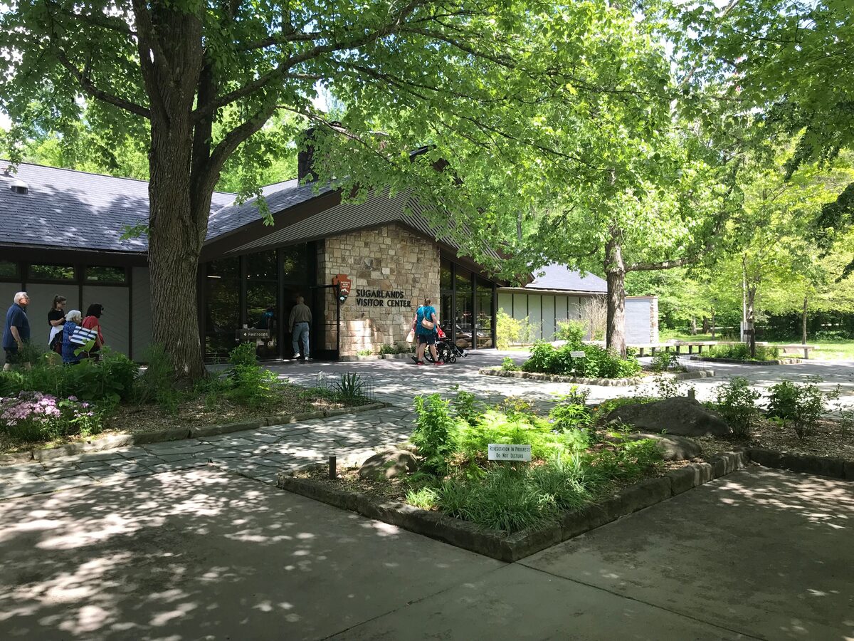 Sugarlands Visitor Center entrance with its stone chimney, framed by summer trees