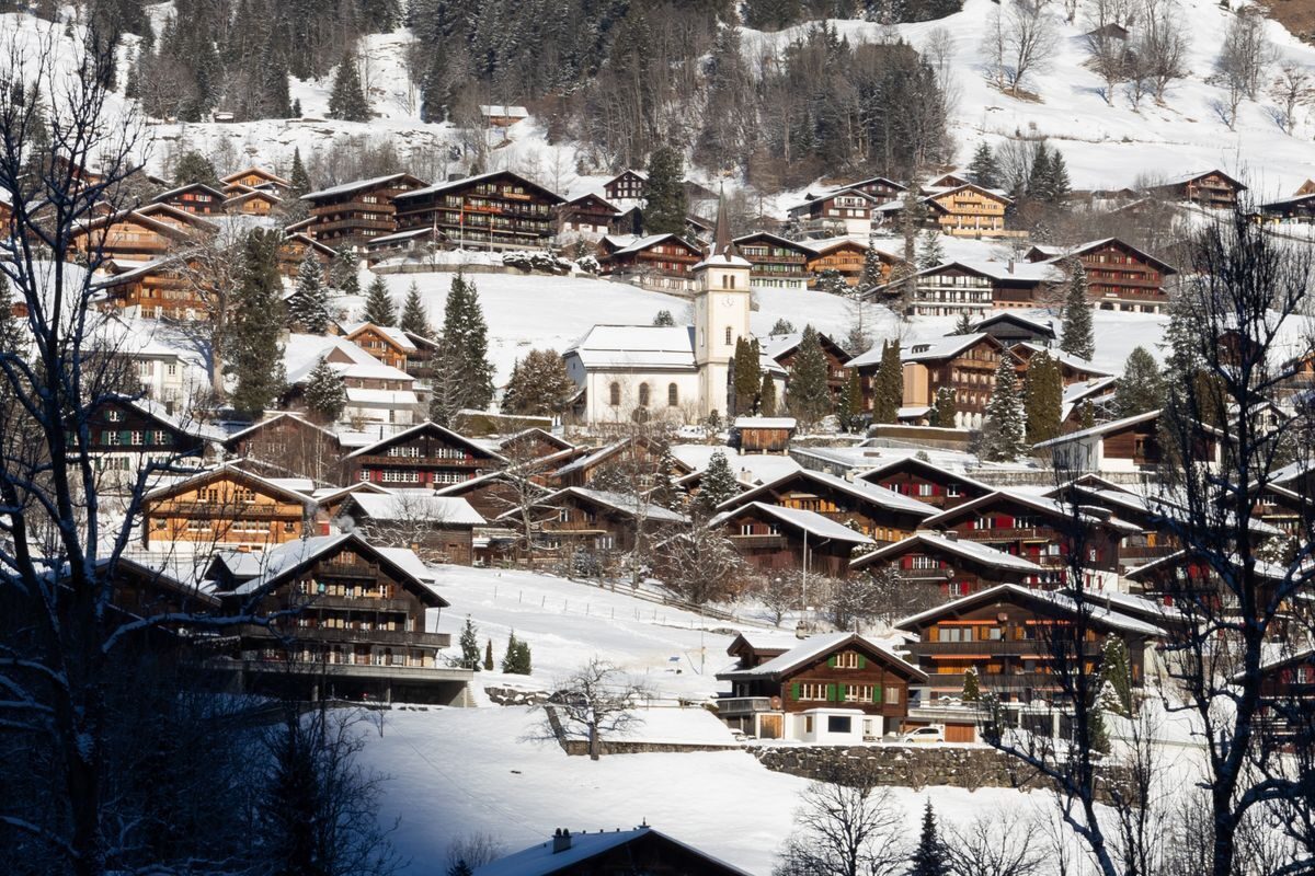 Snowy chalets and the village church of Grindelwald on a sunny winter day