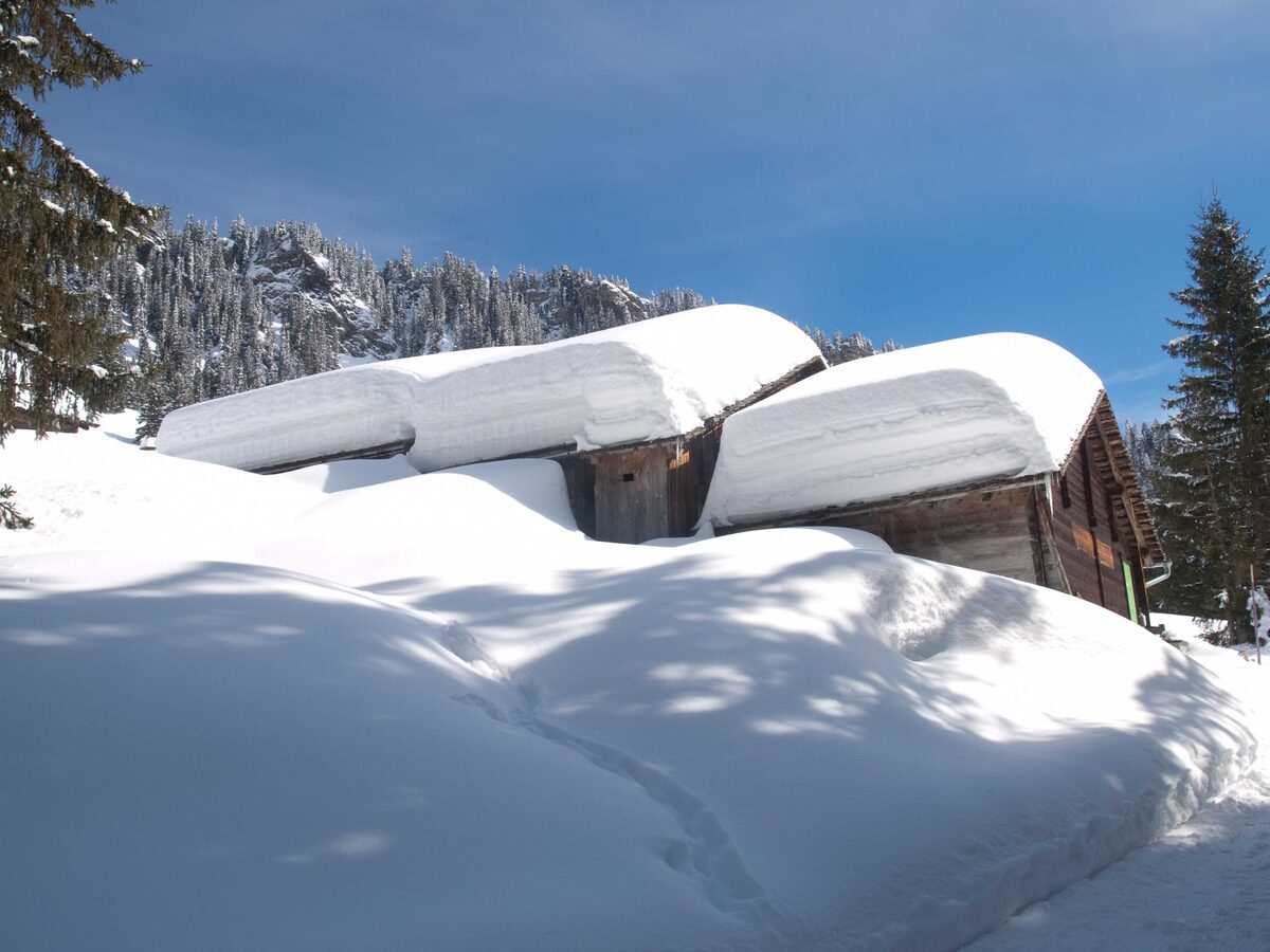 Old wooden huts under deep snow on a slope above Grindelwald