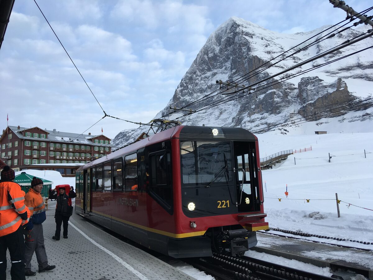 A red Jungfrau Railway train at Kleine Scheidegg in snow with the Eiger above