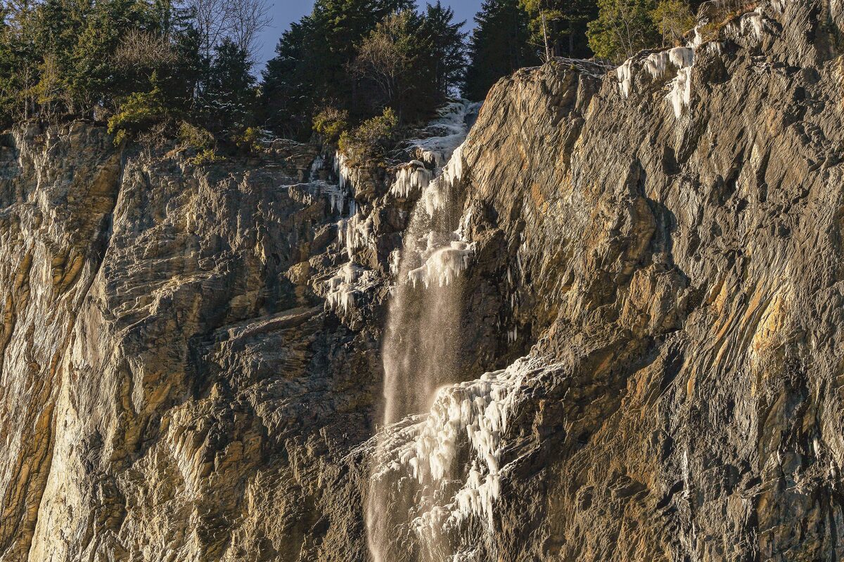 The Staubbach Falls down a rock face beside snow-dusted trees in winter