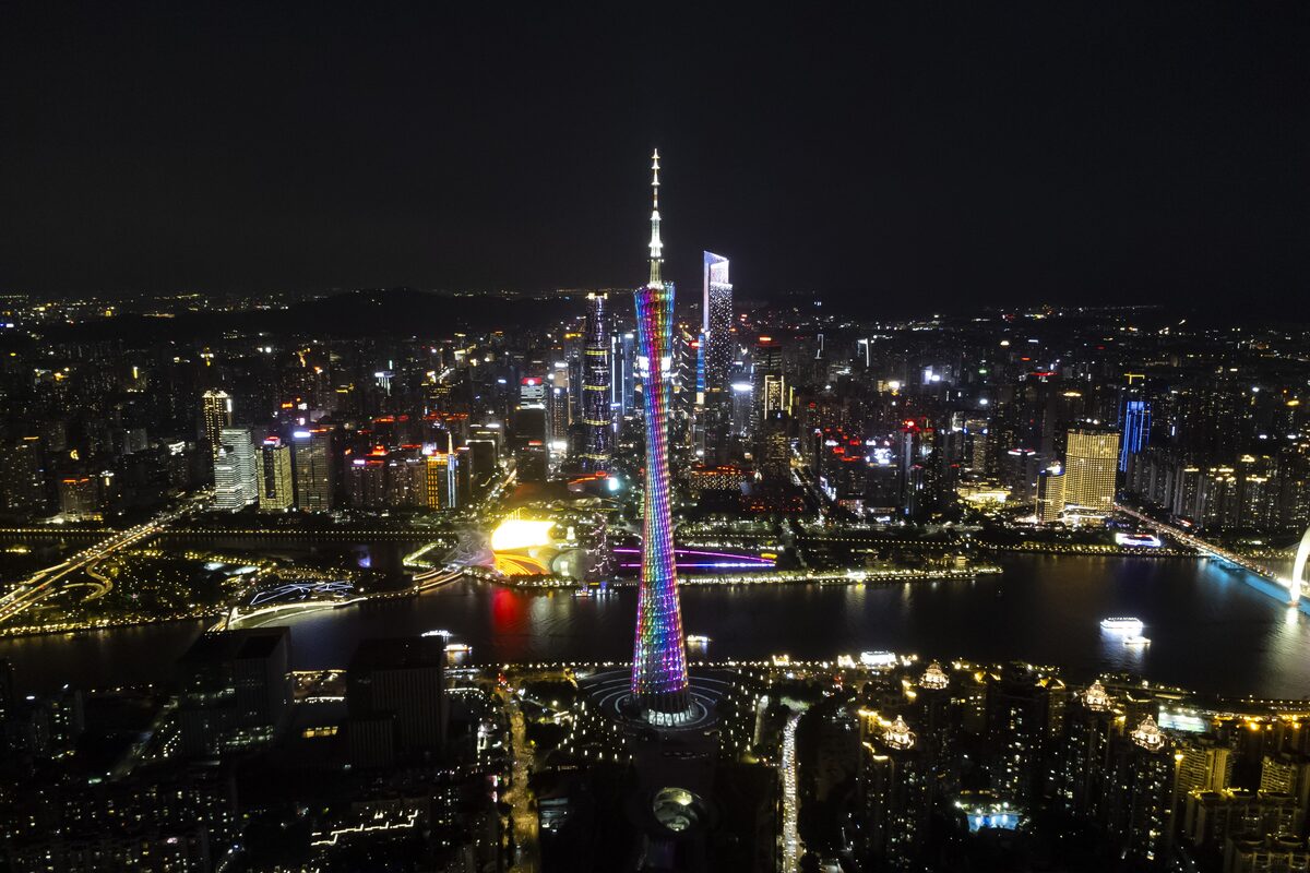 Canton Tower lit up in rainbow colors at night beside the Pearl River, with the glowing Zhujiang New Town skyline around it