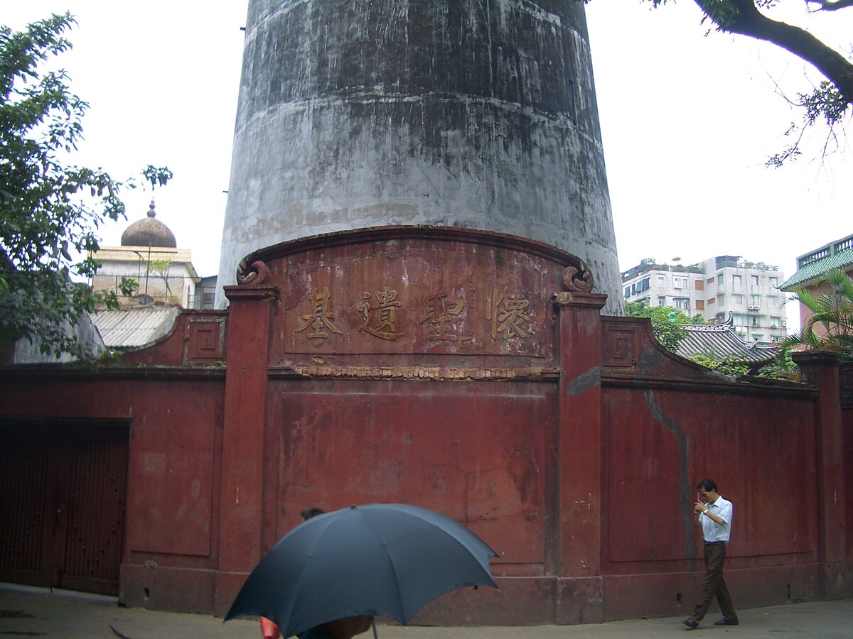 The red outer wall of Huaisheng Mosque with the weathered grey base of its Guangta minaret rising behind it