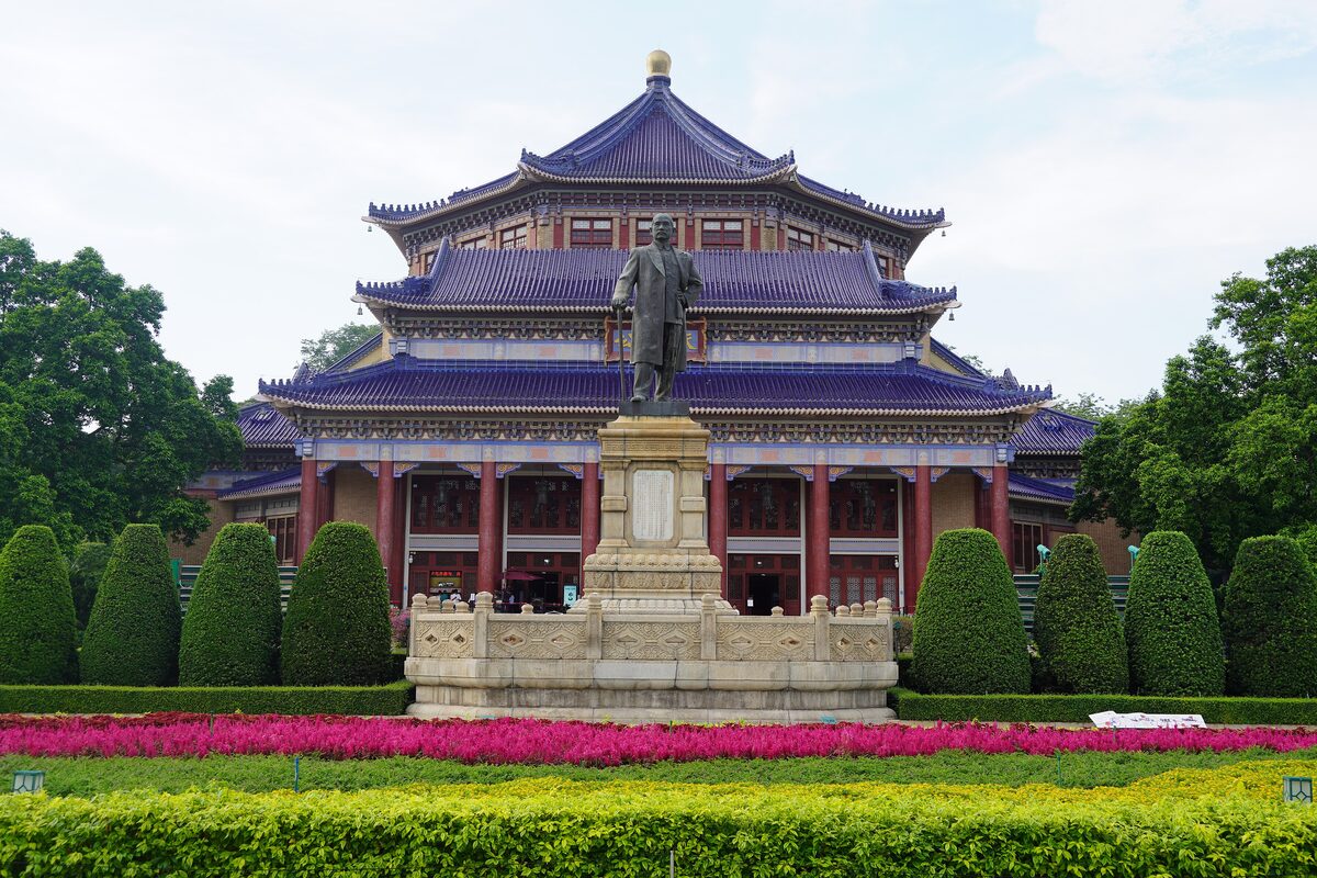 The blue-tiled octagonal roof of the Sun Yat-sen Memorial Hall behind the statue and flower beds