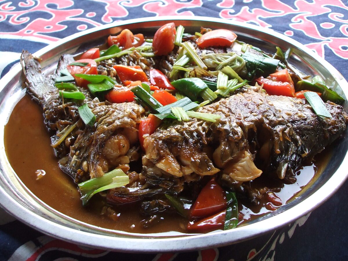 A platter of beer fish, river fish braised with tomato, green chili and spring onion in a brown sauce