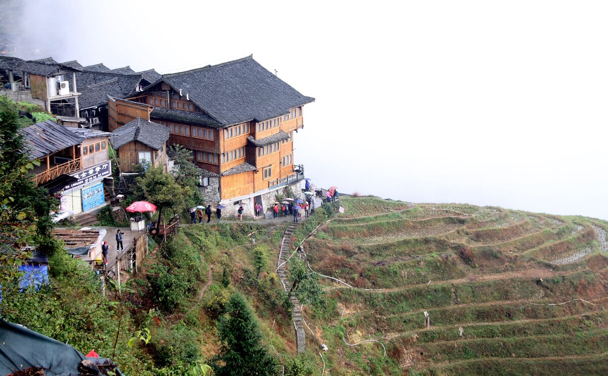 Wooden houses of Ping'an village perched on the edge of the Longji rice terraces on a misty day