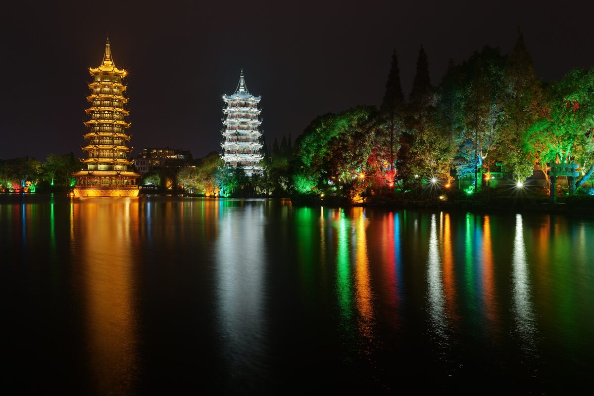 The lit Sun and Moon Pagodas reflected in the lake in the center of Guilin at night