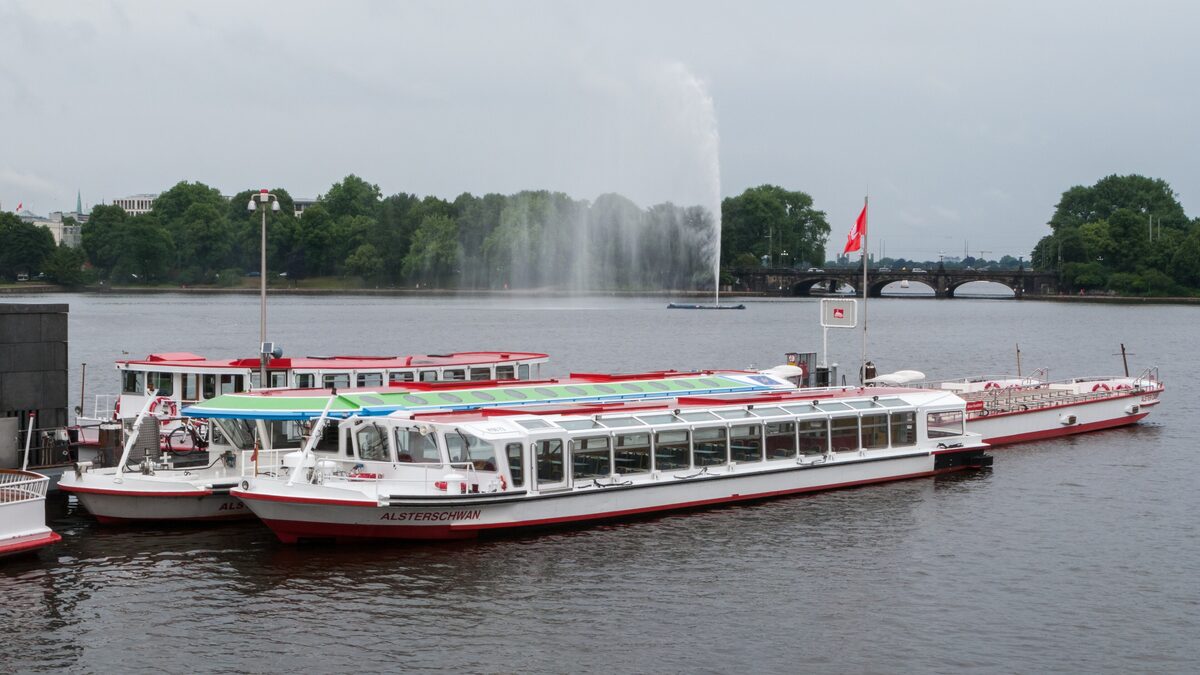 White excursion boats moored on the Binnenalster with the Alster fountain behind them