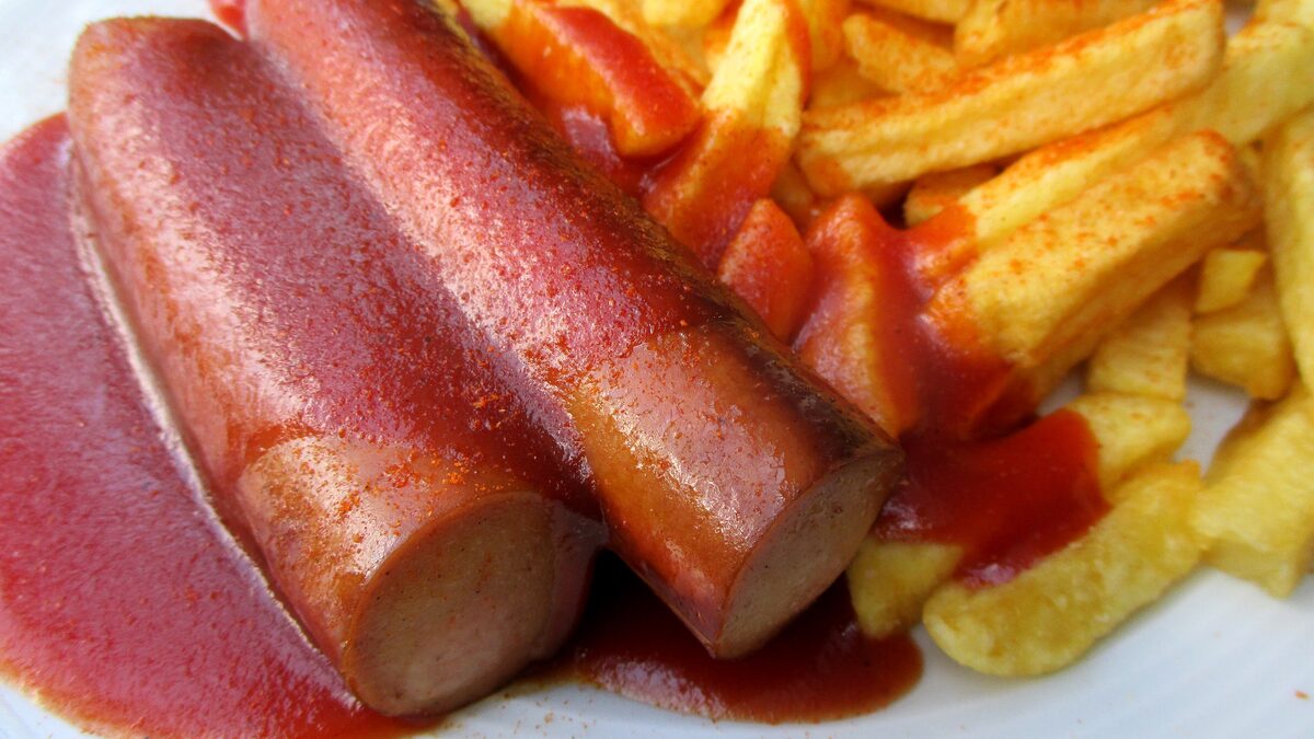Two grilled sausages in curry-spiced ketchup with fries