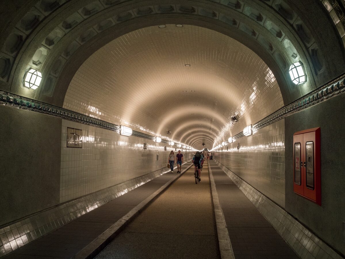 Looking down the tiled tube of the Old Elbe Tunnel, with a few cyclists and walkers in the distance
