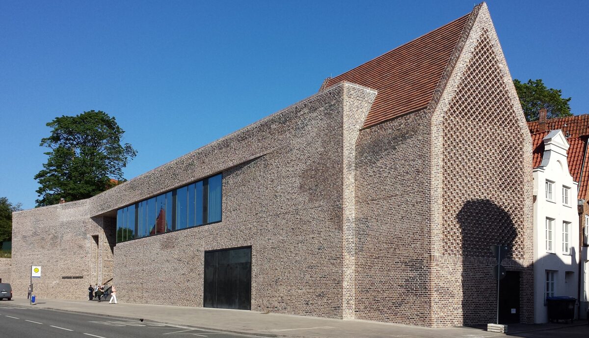 The long windowless brick facade of the European Hansemuseum in Lübeck, with a lattice pattern in its end wall