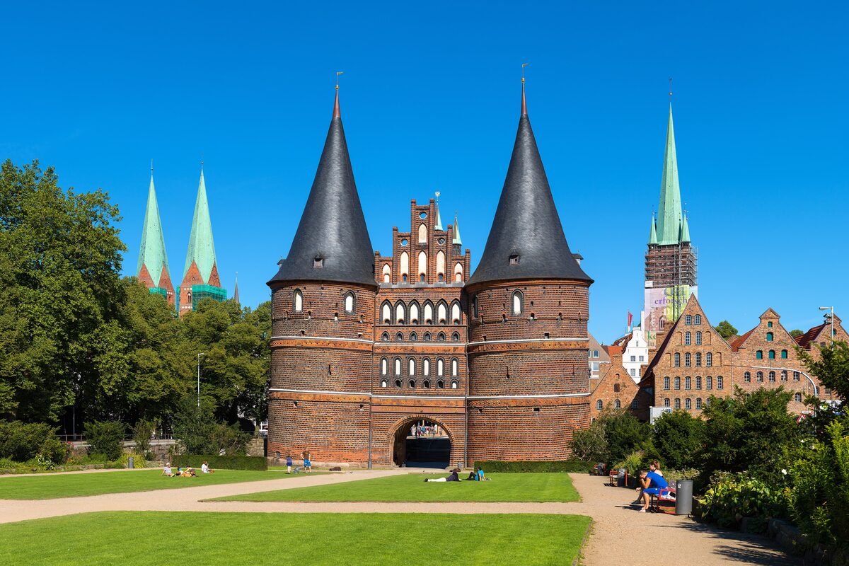 The two round towers and gabled brick hall of the Holstentor in Lübeck, with church spires rising behind