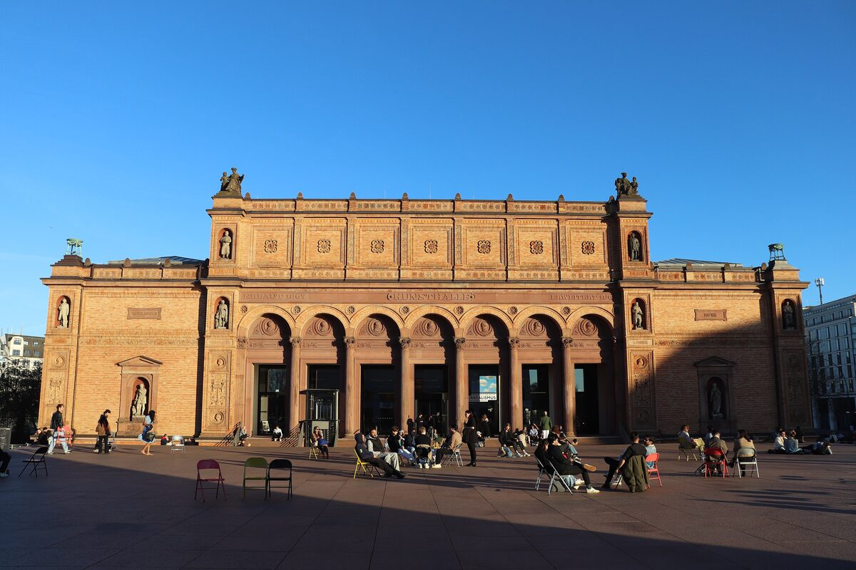 The sandstone front of the Hamburger Kunsthalle with its arcade and people sitting on the square in evening light