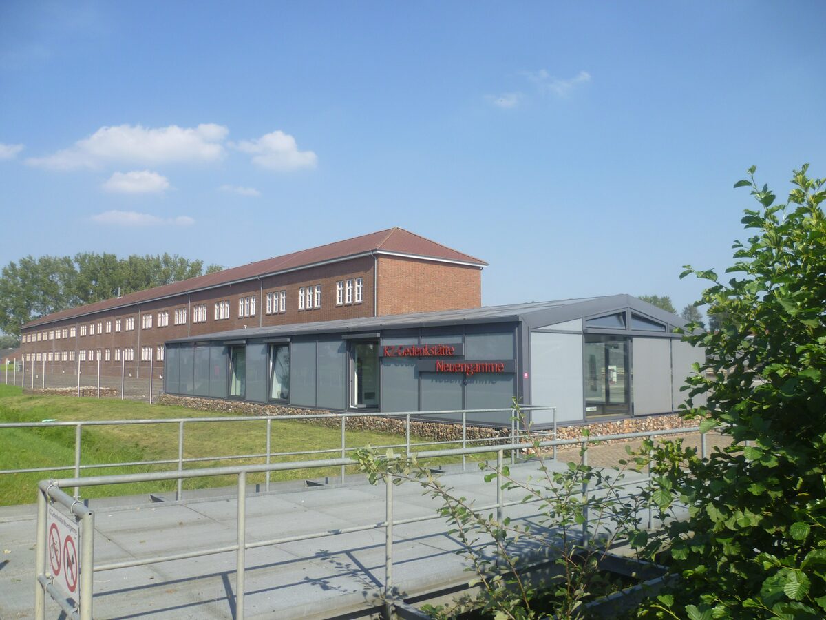The entrance building and the long brick halls of the Neuengamme memorial site on a clear day