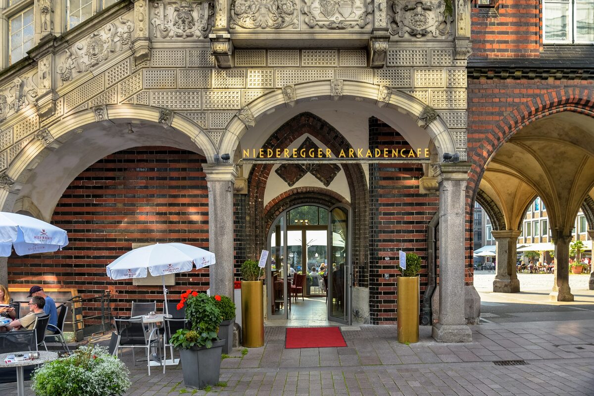 The ornate arcaded entrance of the Niederegger Arkadencafé on Lübeck's market square, with tables outside