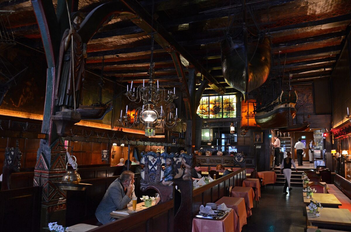 The dark timbered dining hall of the Schiffergesellschaft in Lübeck, with model ships hanging from the ceiling