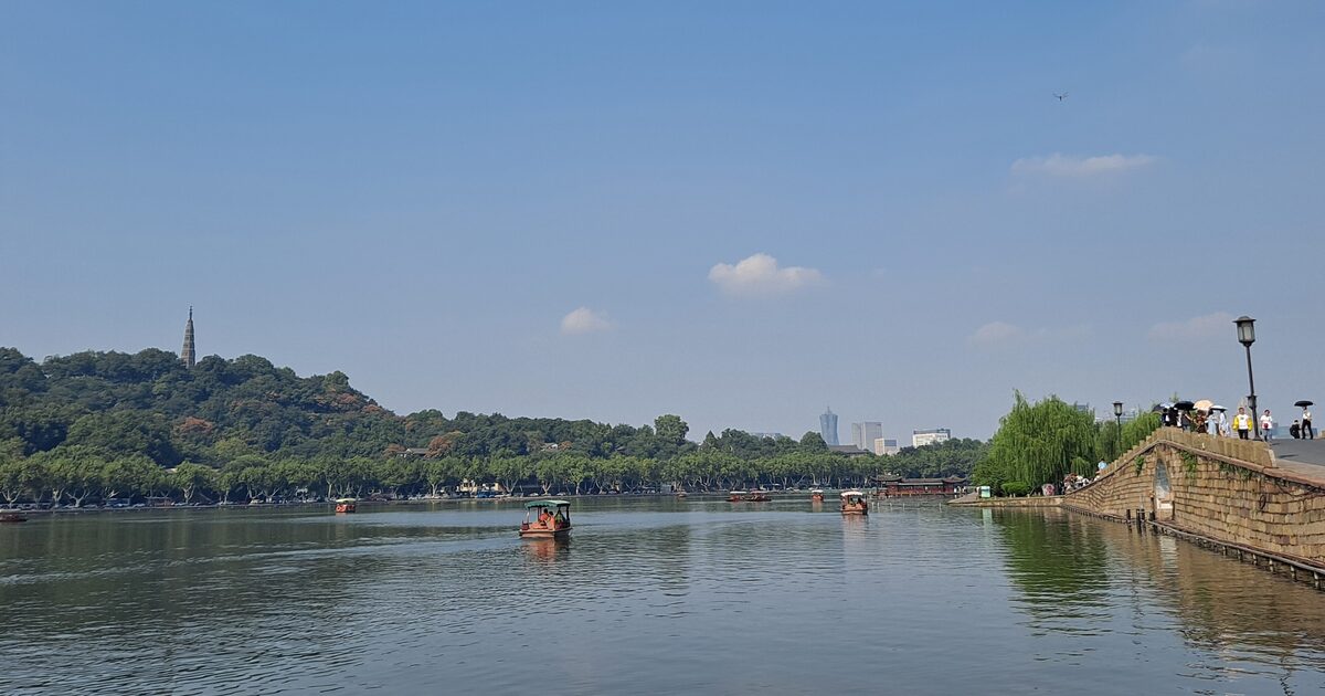 The wooded hill and Baochu Pagoda across the water of West Lake beside the stone arch of Broken Bridge