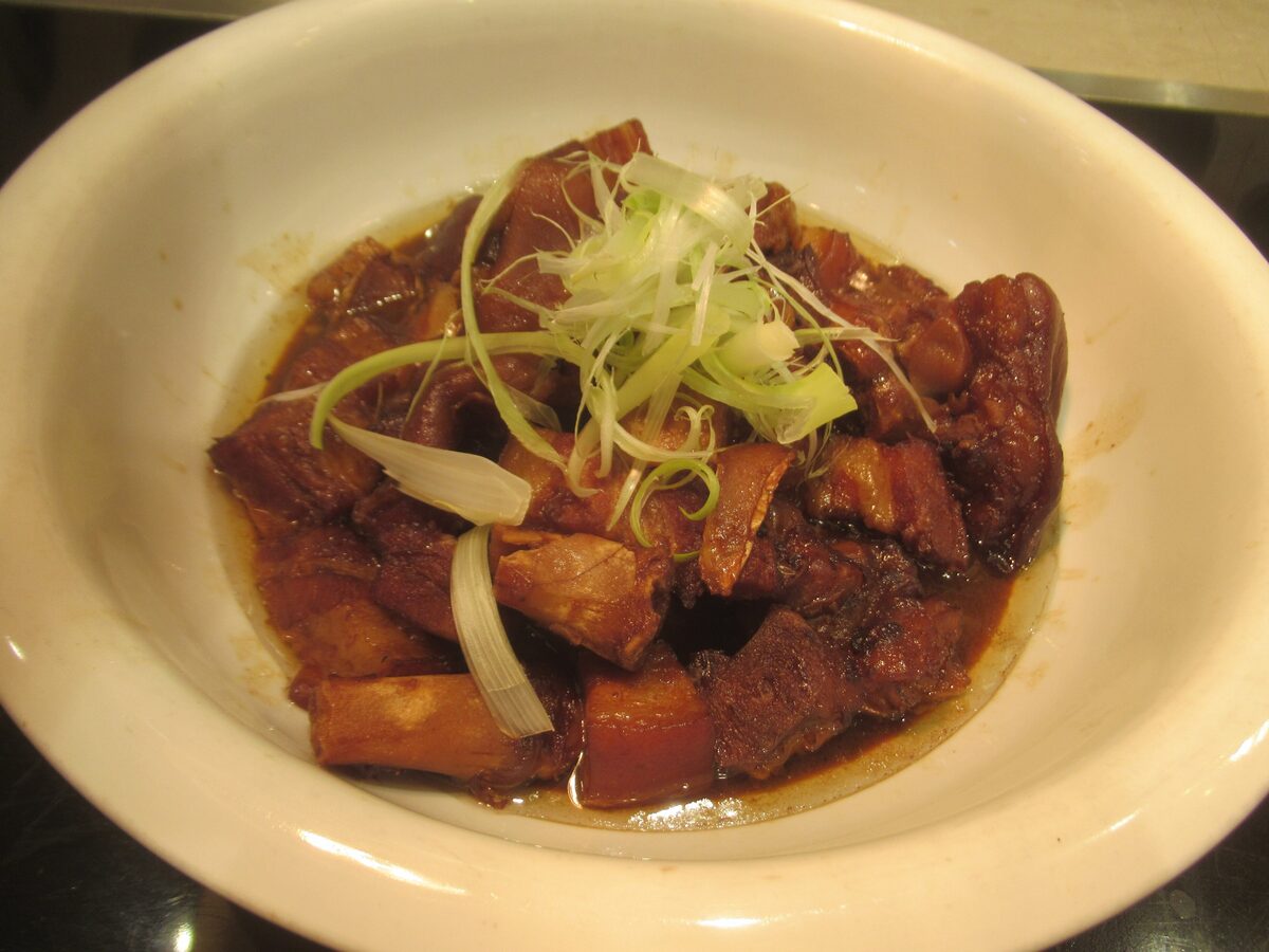 Braised Dongpo pork in a white bowl, topped with strips of spring onion