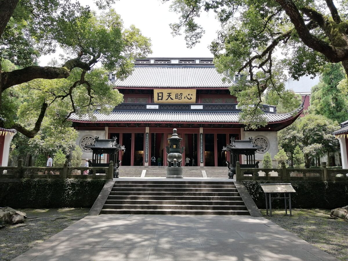 The main hall of Yue Fei Temple with a bronze incense burner on the stone steps, framed by old trees